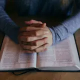 Hands praying over the Bible